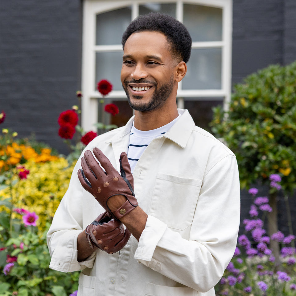 Man wearing brown leather driving gloves in a floral garden