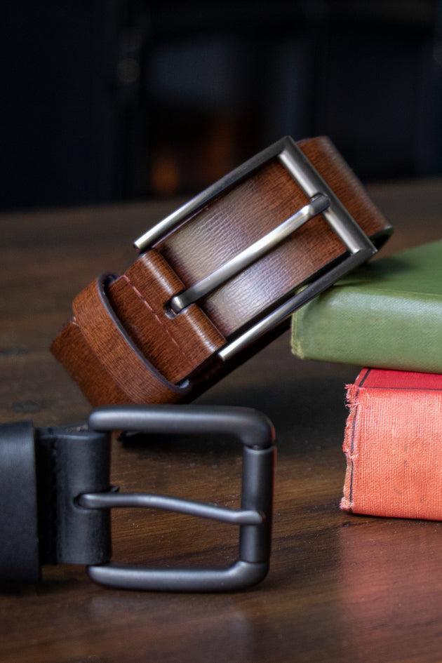 Brown and black leather belts on a wooden table