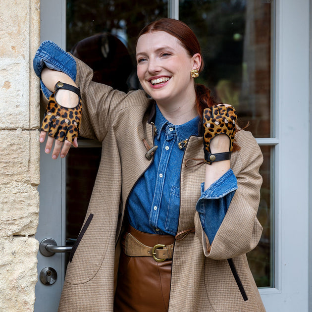 Woman wearing leopard print leather fingerless driving gloves standing in a doorway