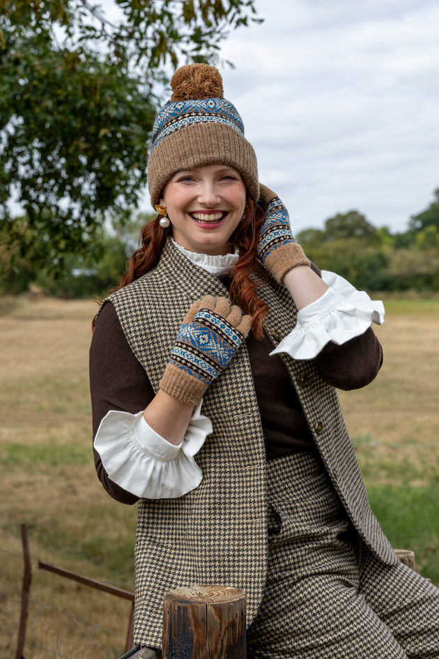 Woman wearing a fair isle knitted bobble hat and matching gloves in the countryside