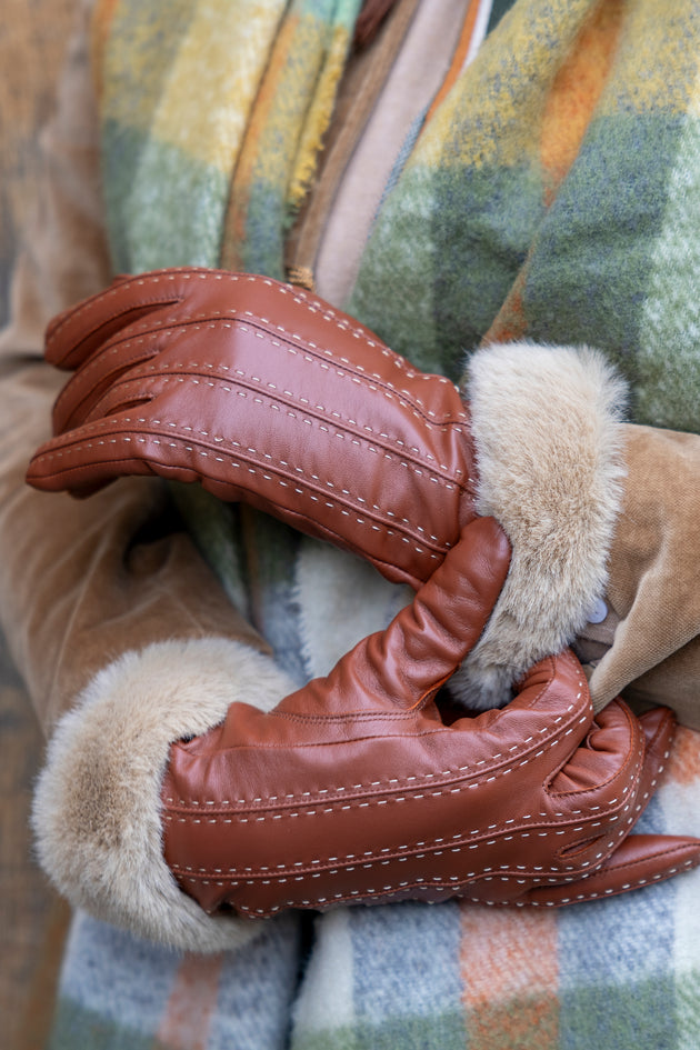 Close-up of women's brown leather gloves with faux fur cuffs